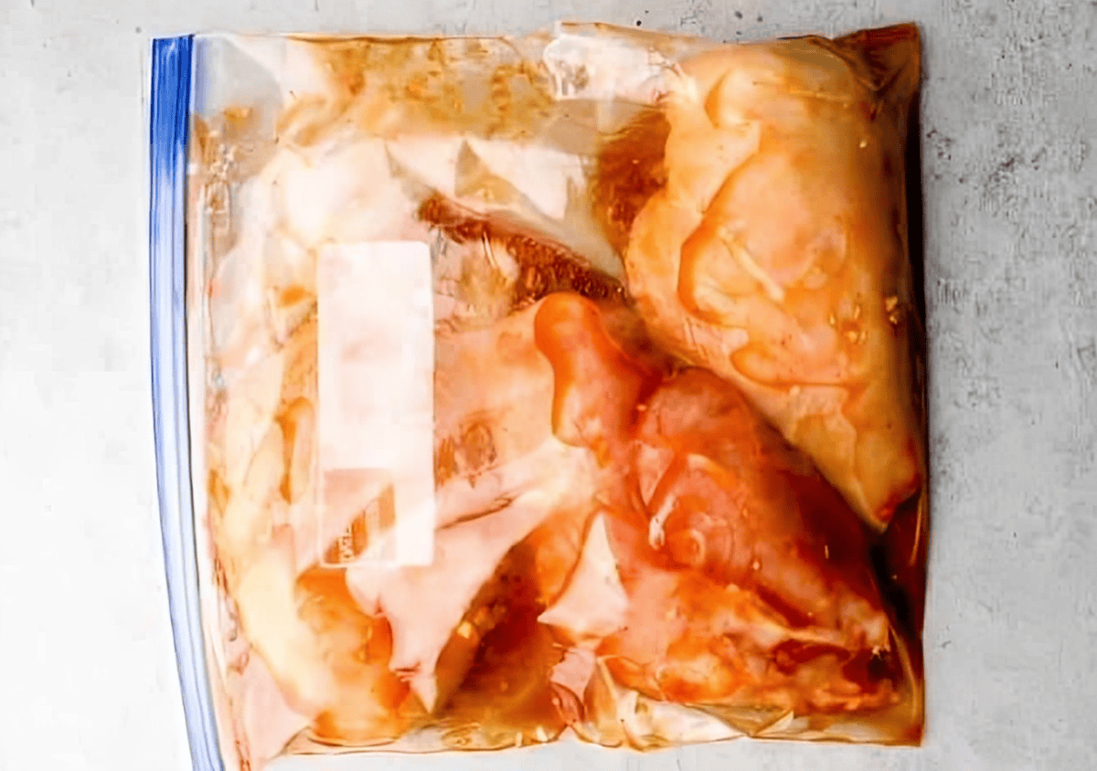 chicken breasts marinating in bbq sauce in a ziplock bag.