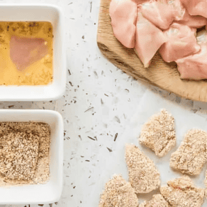 breading cut chicken nuggets in egg and breadcrumbs.