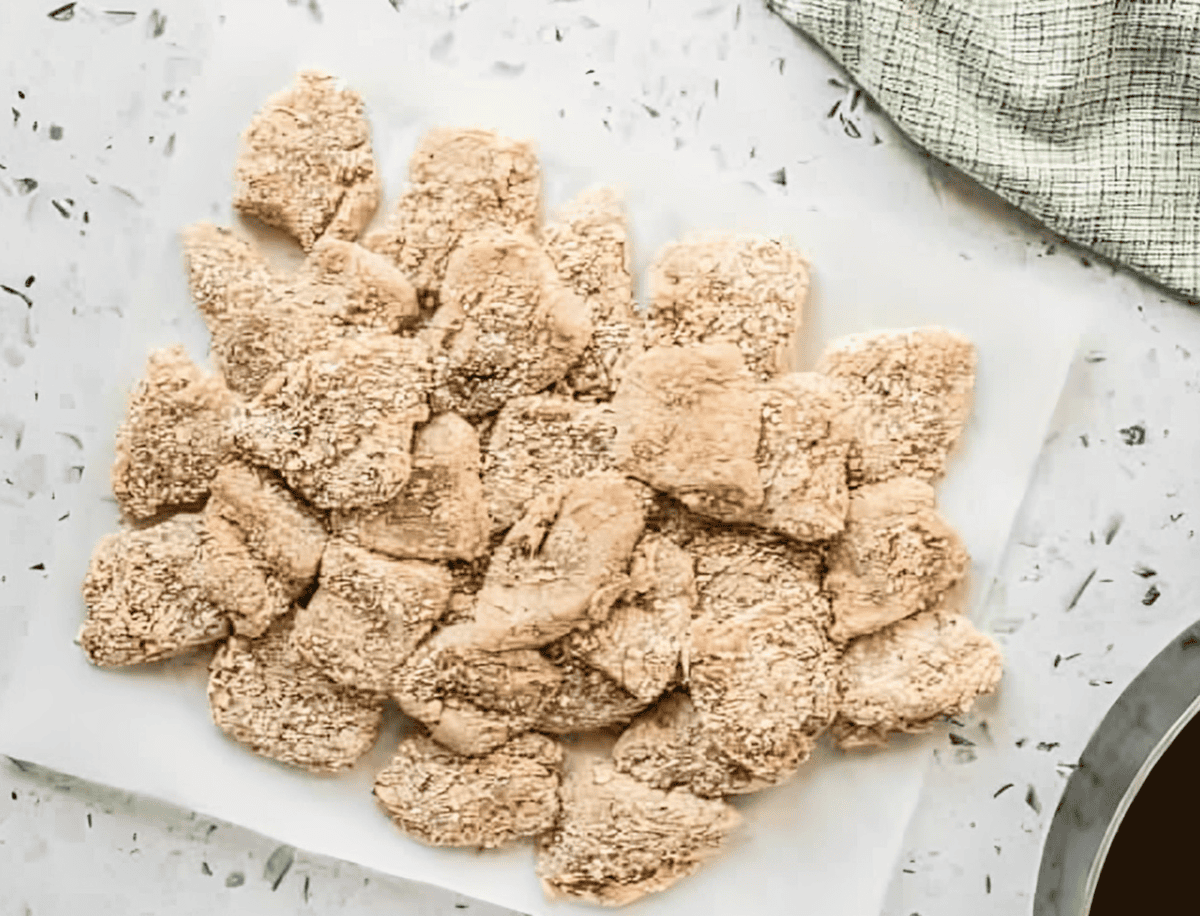 breaded raw chicken nuggets on a white plate.