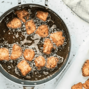 frying chicken nuggets in a skillet.