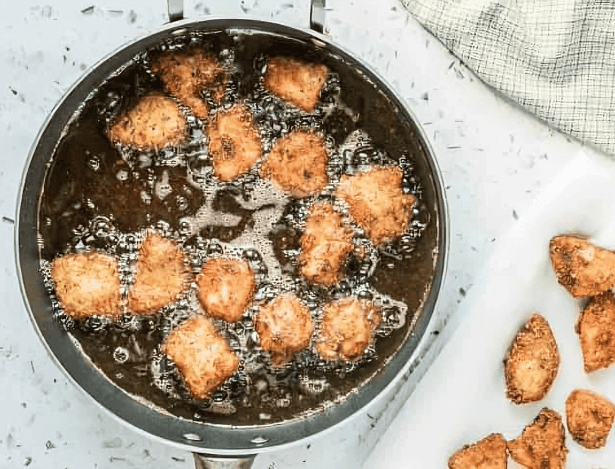 frying chicken nuggets in a skillet.