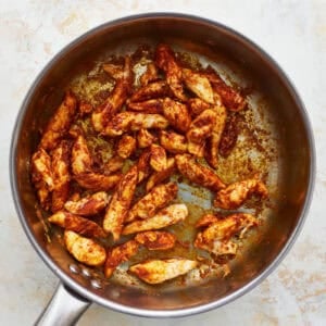 seared seasoned chicken strips in a skillet.