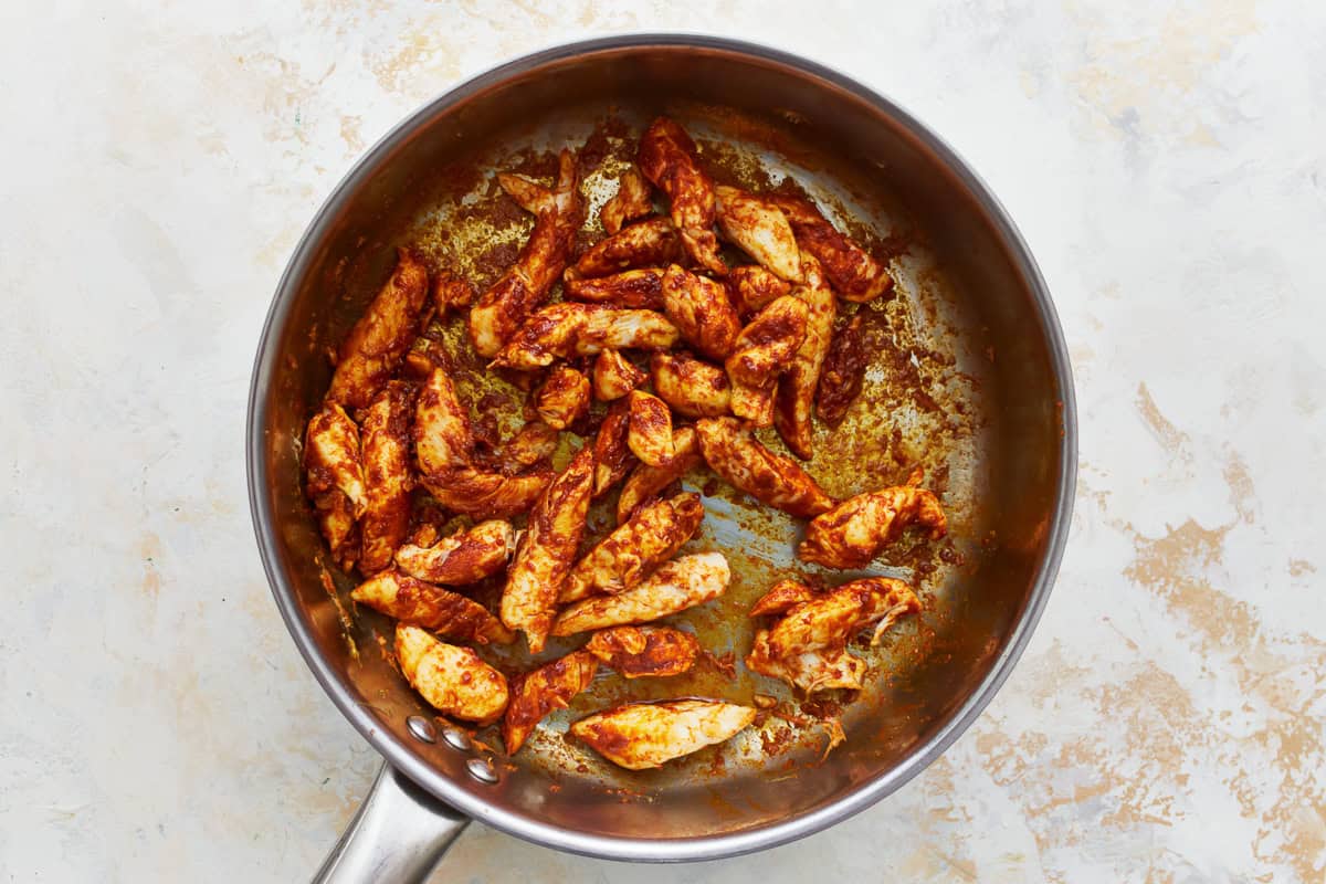 seared seasoned chicken strips in a skillet.