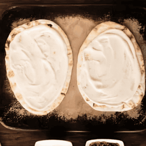 2 naan flatbreads spread with Alfredo sauce.