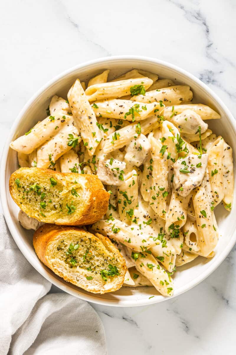 chicken pasta in bowl with garlic bread
