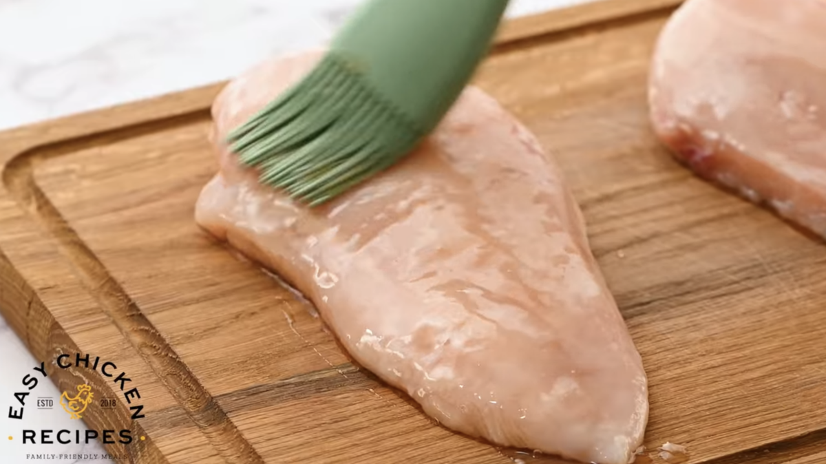 Maple syrup is being brushed onto a chicken breast. 