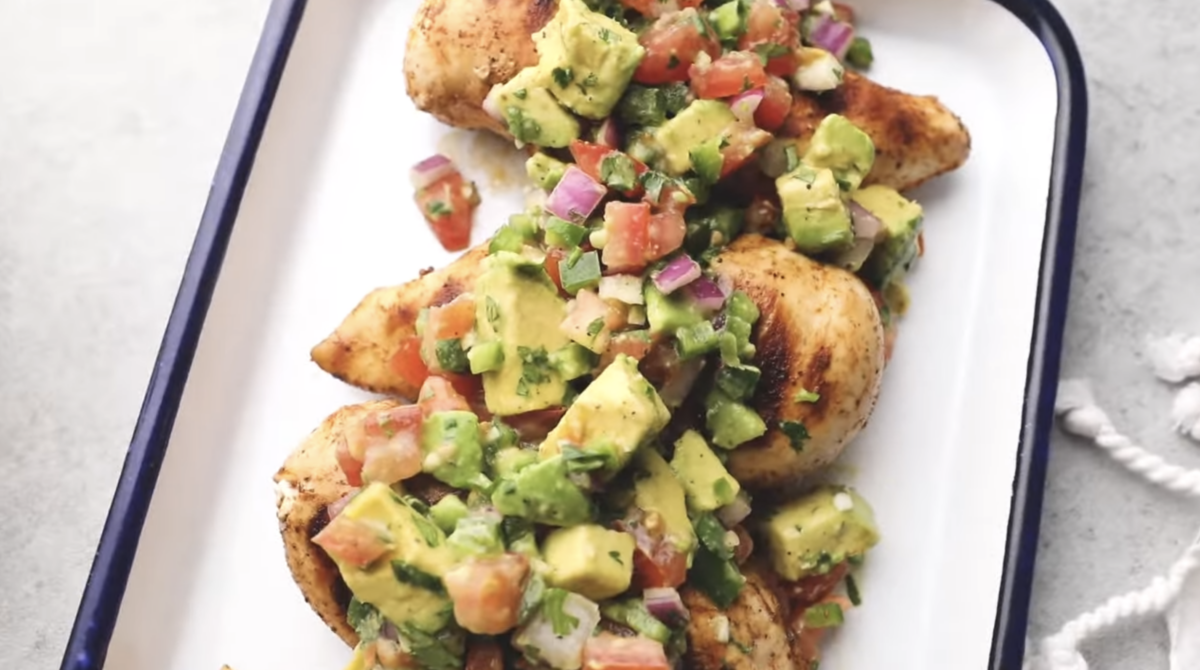 Avocado salsa is spread across the top of cooked chicken breasts. 
