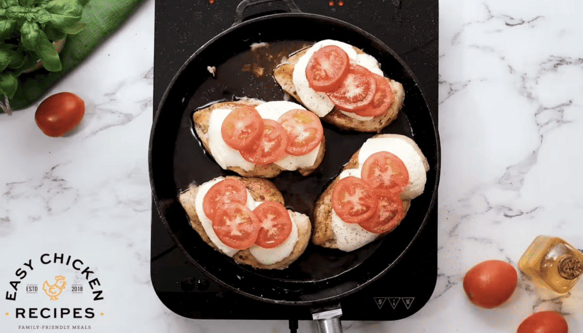 Mozzarella and tomatoes have been added to the tops of chicken breasts. 