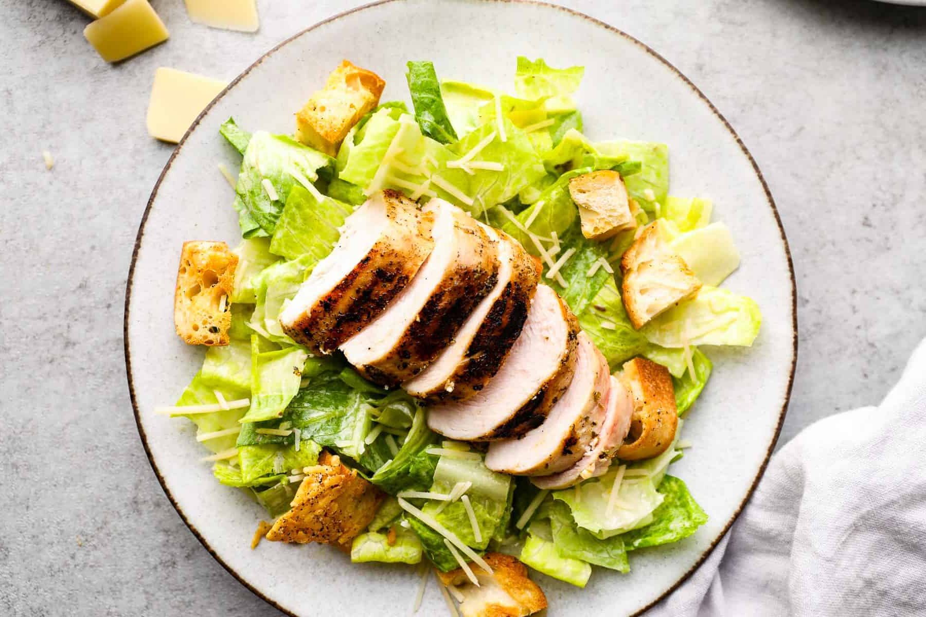 overhead image of grilled chicken caesar salad on white plate