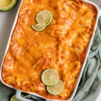 chicken enchilada casserole in baking dish with lime slices