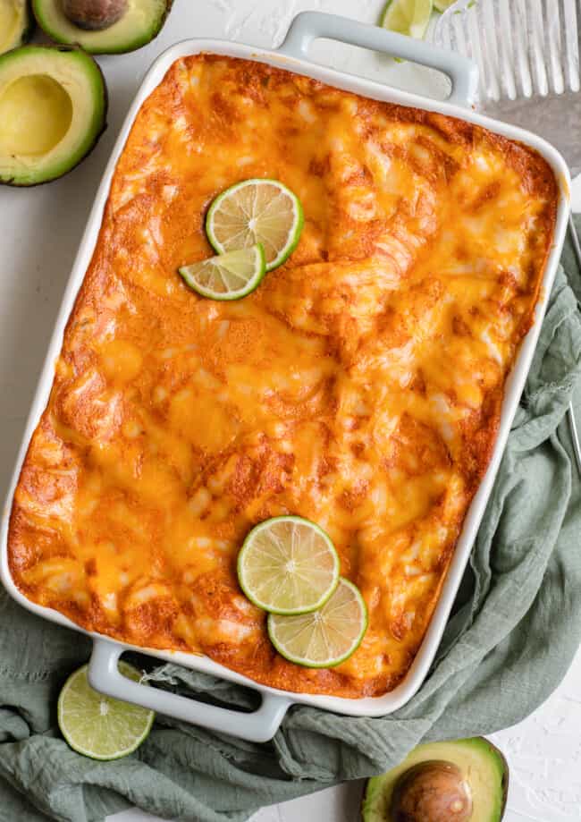 chicken enchilada casserole in baking dish with lime slices