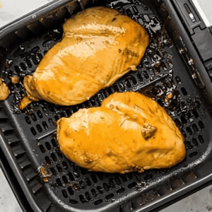 cooked chicken breasts in an air fryer basket.