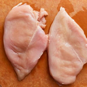 raw chicken breasts on a cutting board.