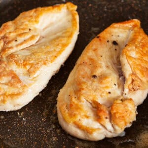 2 cooked chicken breasts in an oiled skillet.