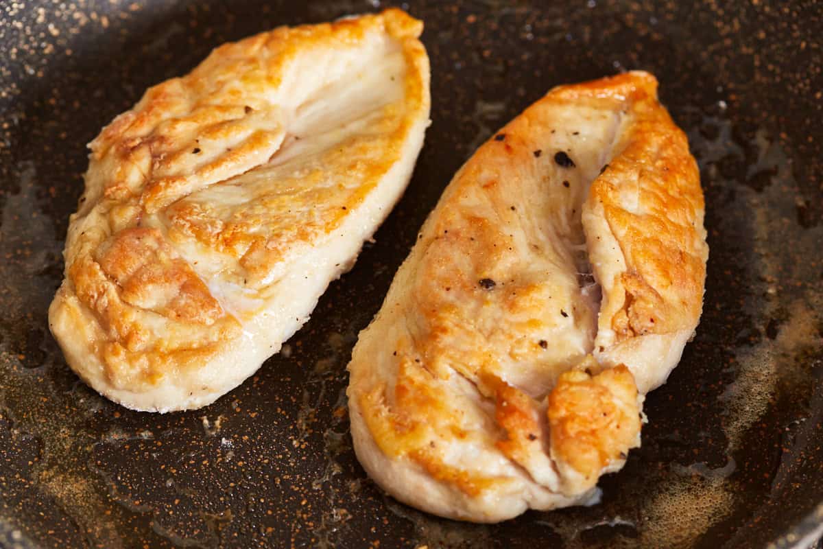 2 cooked chicken breasts in an oiled skillet.