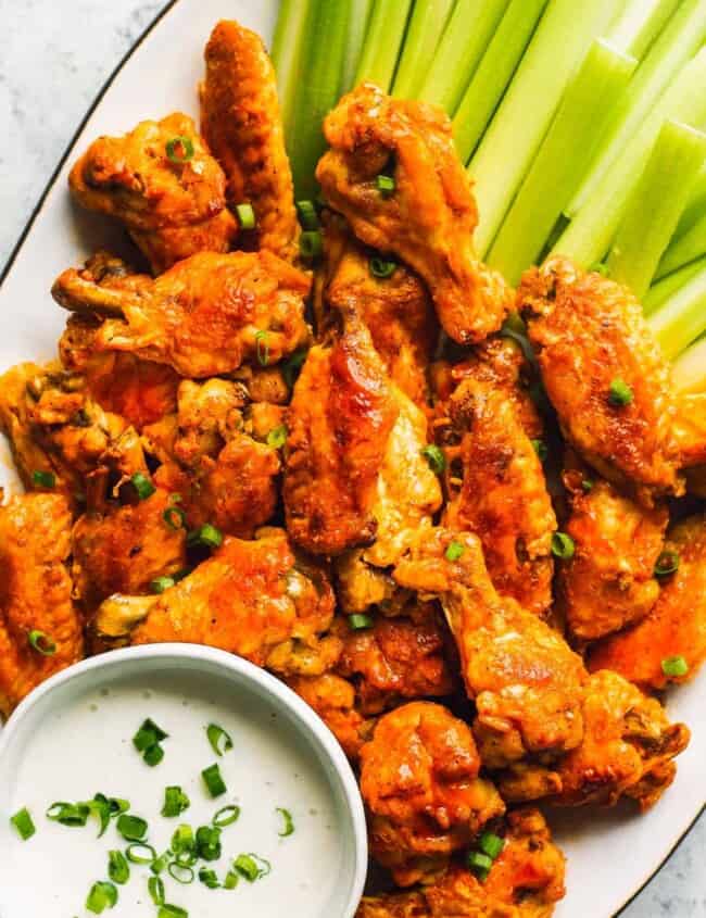 buffalo wings on white platter with dip