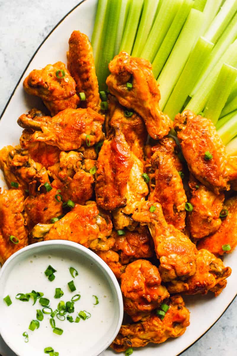 buffalo wings on white platter with dip