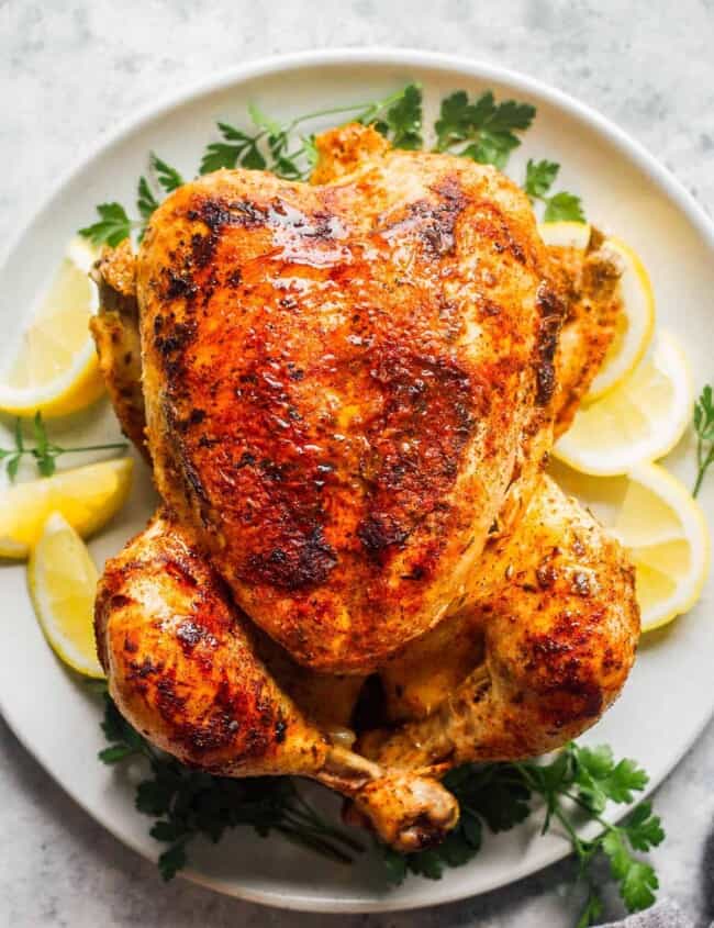 seasoned whole chicken with lemon on white plate