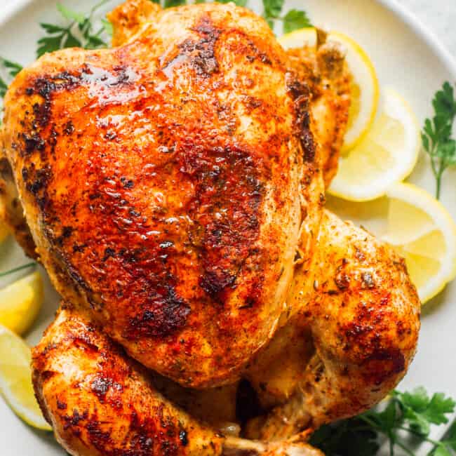seasoned whole chicken with lemon on white plate
