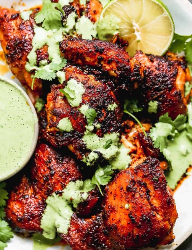 up close image of spiced peruvian chicken drizzled with green sauce