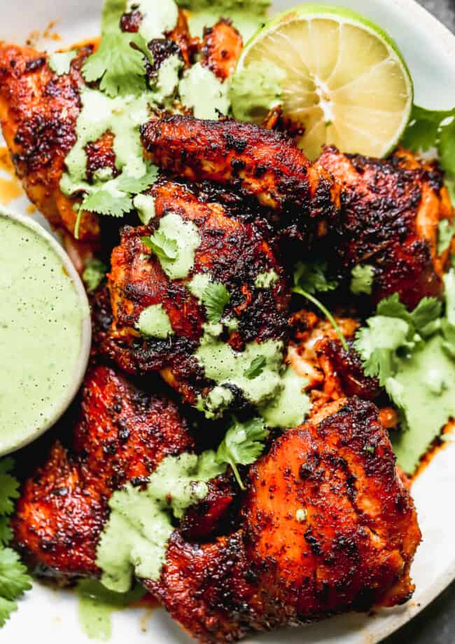 up close image of spiced peruvian chicken drizzled with green sauce