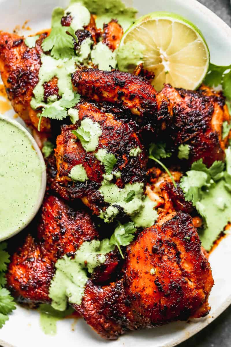 up close image of spiced peruvian chicken drizzled with green sauce