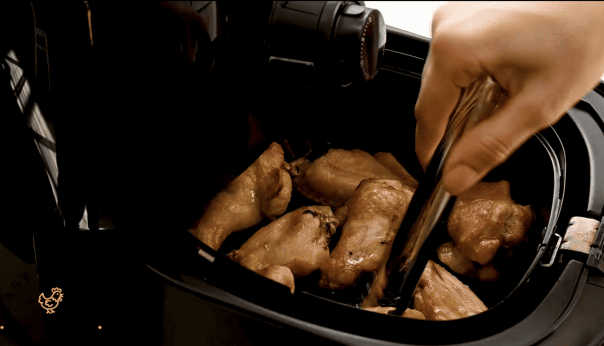 Chicken wings are being cooked in an air fryer. 