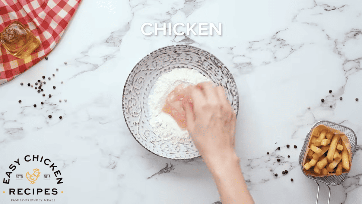 Raw chicken is being dipped in flour. 