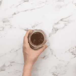 A person holding a jar of chocolate ganache with lemons.