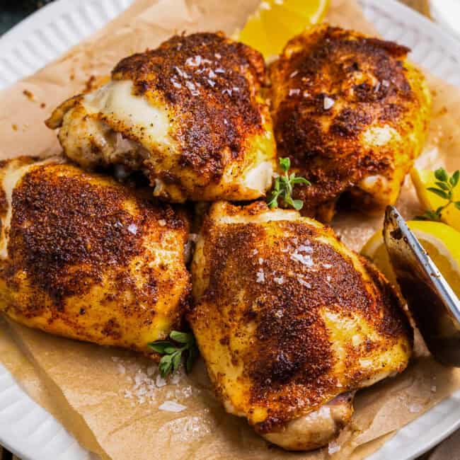 air fryer chicken thighs on a parchment lined plate.