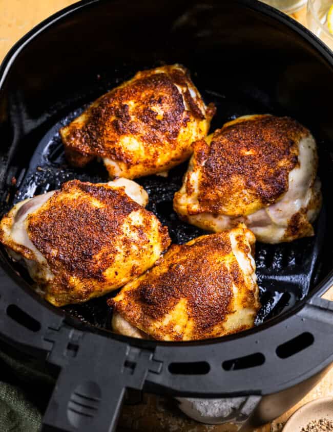 cooked chicken thighs in an air fryer basket.