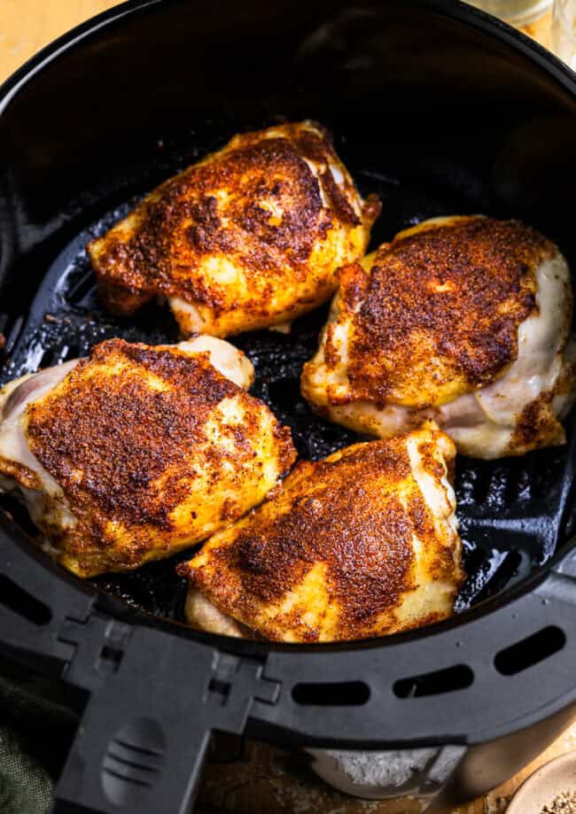 cooked chicken thighs in an air fryer basket.