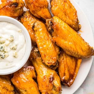overhead view of air fryer buffalo wings on a white plate with blue cheese dressing.