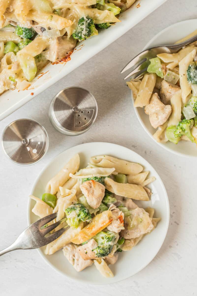 two plates with chicken and broccoli pasta
