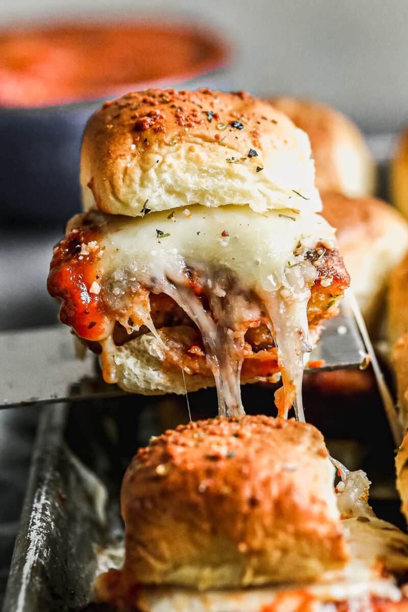 Close up image of chicken parm slider with cheese pull.