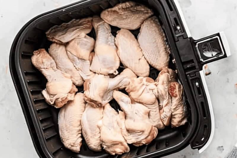raw chicken wings arranged in a single layer in an air fryer.