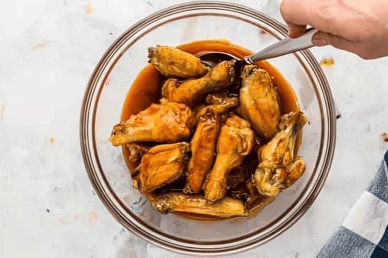 tossing air fryer chicken wings in buffalo sauce.
