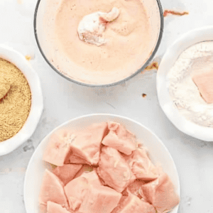 dredging raw chicken nuggets in flour, batter, and breadcrumbs.