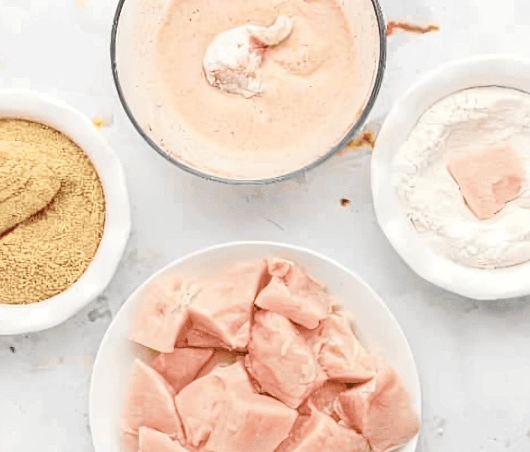 dredging raw chicken nuggets in flour, batter, and breadcrumbs.