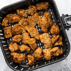 cooked chicken nuggets in an air fryer basket.