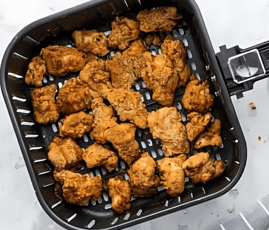 cooked chicken nuggets in an air fryer basket.