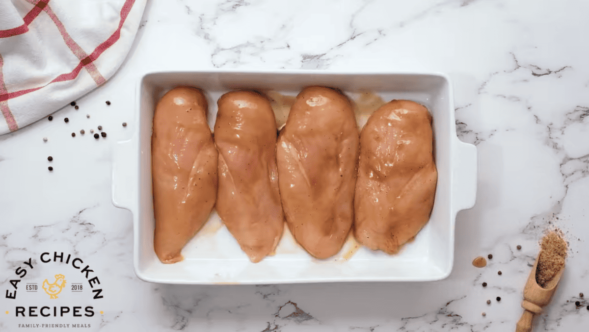 Chicken breasts are lined up in a baking dish. 
