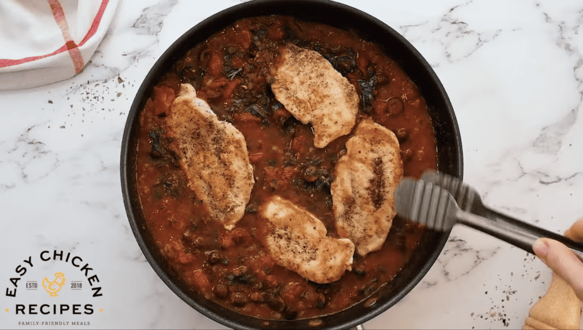A skillet filled with chicken and tomato sauce.