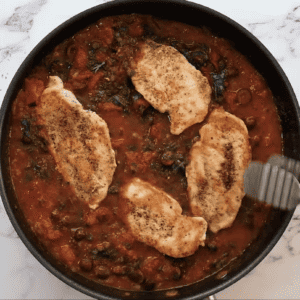 A skillet filled with chicken and tomato sauce.