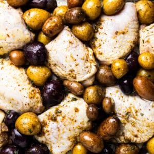 overhead view of unbaked honey mustard chicken thighs and baby potatoes on a sheet pan.