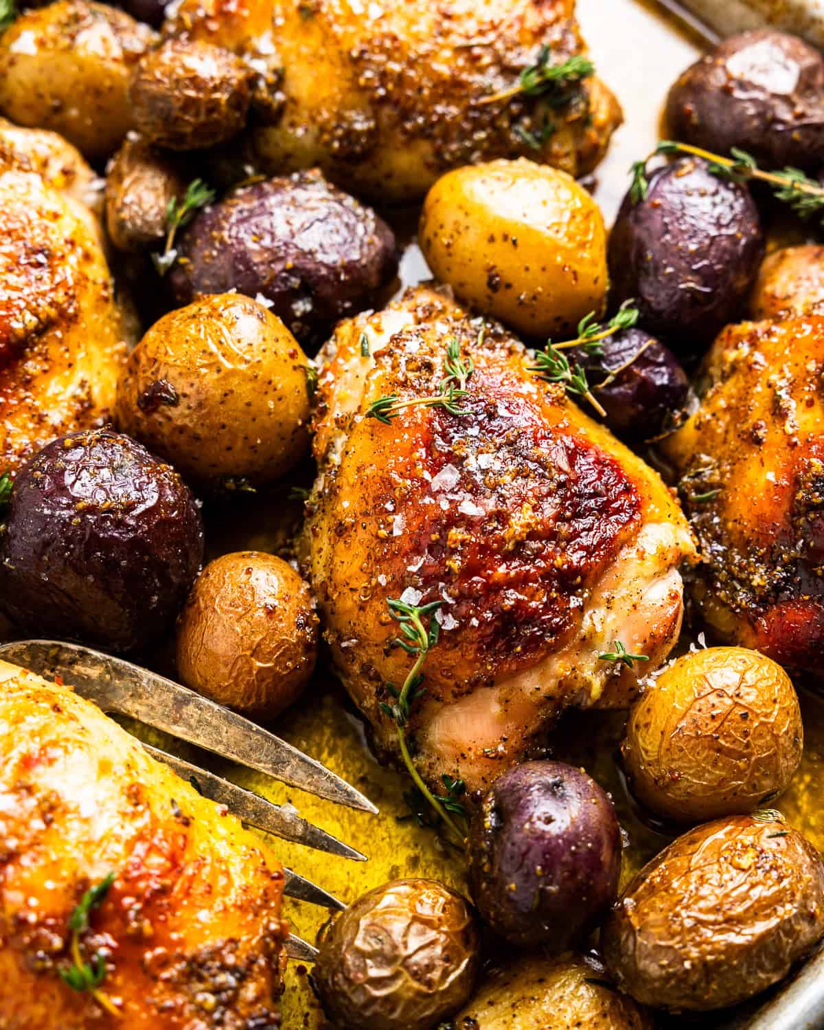 closeup of baked honey mustard chicken thighs and potatoes.