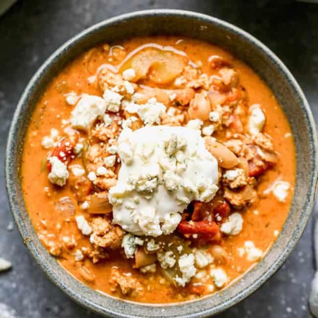buffalo chicken chili in gray bowl topped with blue cheese