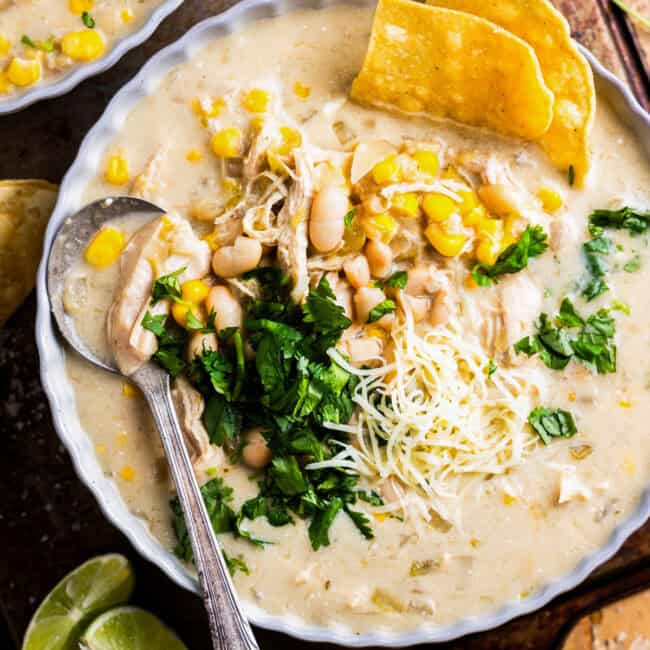 overhead view of a bowl of crockpot white chicken enchilada soup with a spoon.