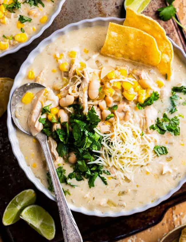 overhead view of a bowl of crockpot white chicken enchilada soup with a spoon.