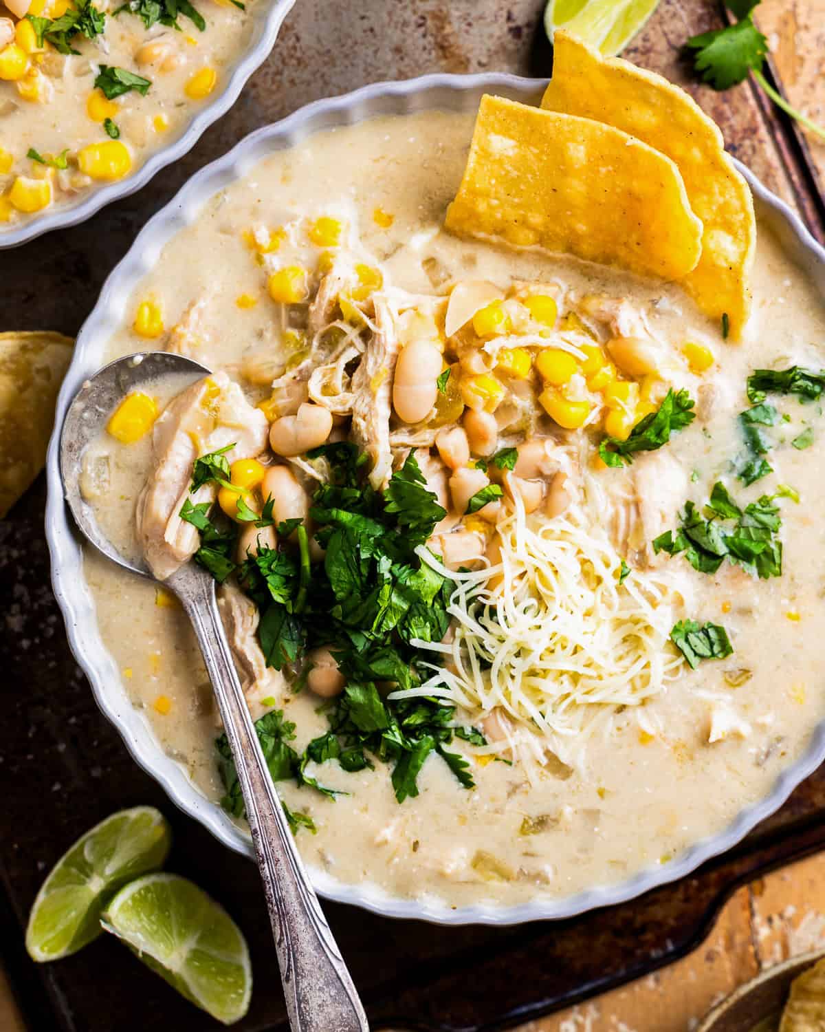 overhead view of a bowl of crockpot white chicken enchilada soup with a spoon.